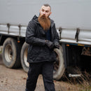 Man wearing original British Military Police waterproof lined rain jacket outdoors near a truck in black parka design