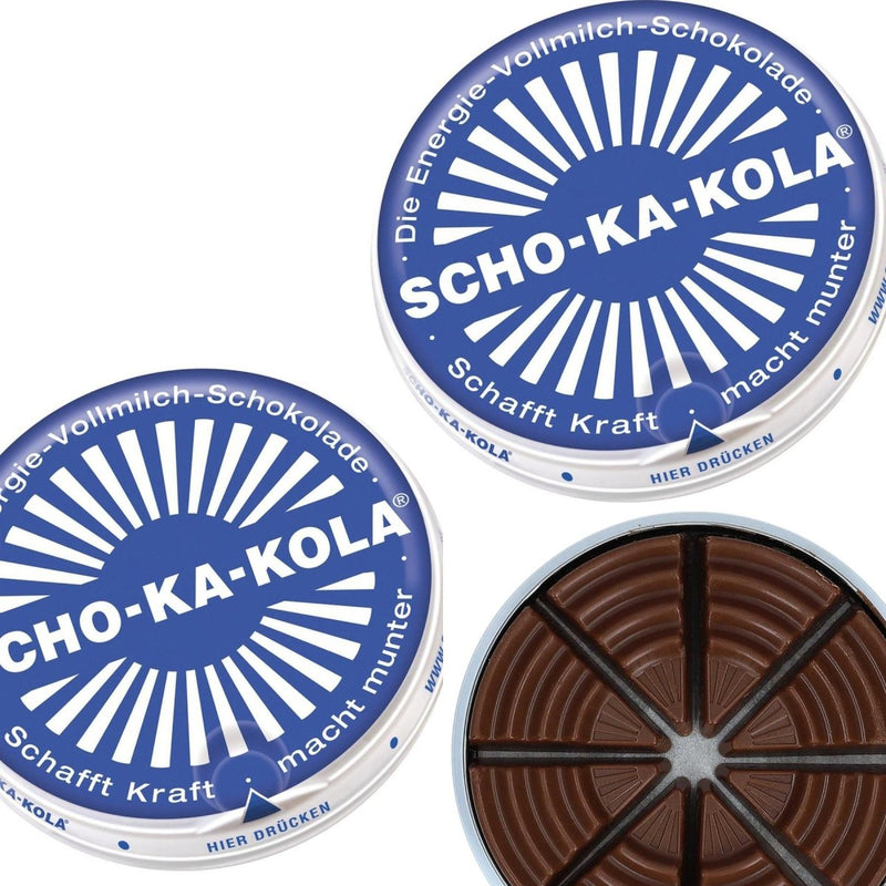 Blue tin can of Scho-Ka-Kola German milk chocolate with caffeine, showing eight wedge-shaped pieces inside.