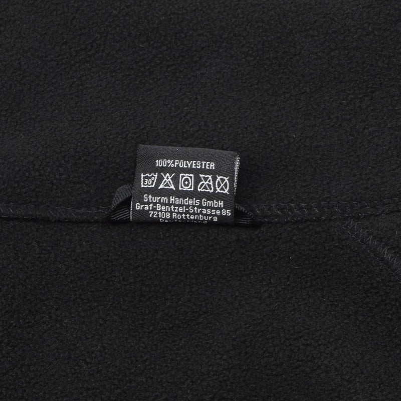 Close-up of black MIL-TEC fleece pullover showing care label and polyester fabric texture