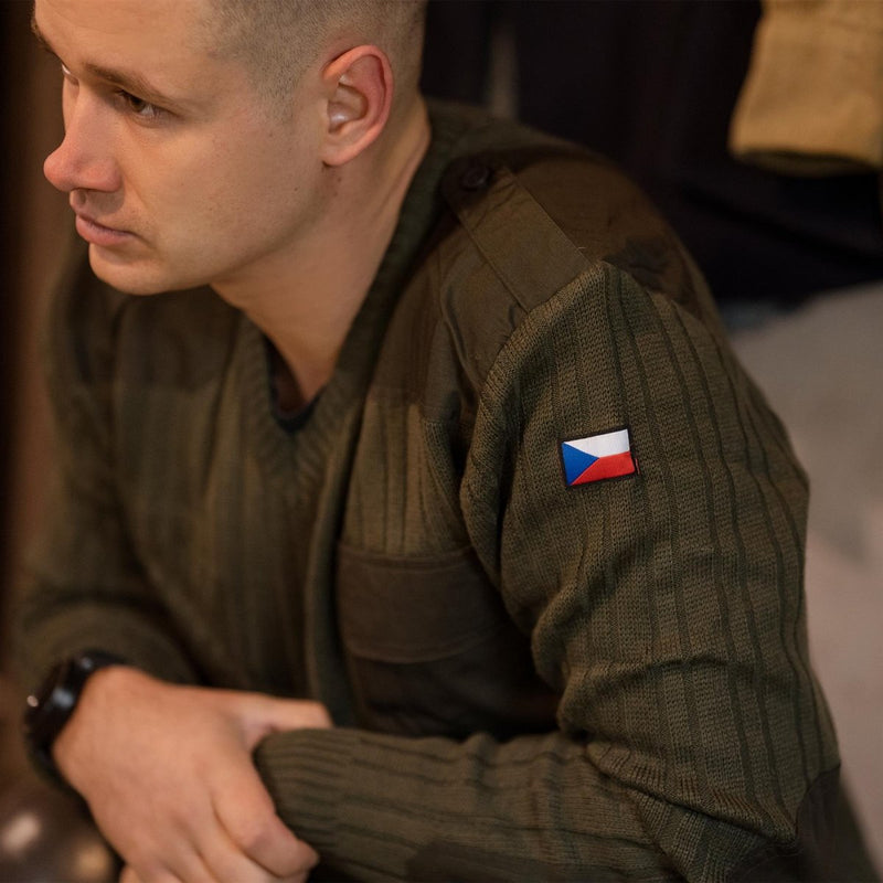 Man wearing olive drab Czech army wool sweater jumper with V-neck and embroidered flag patch on sleeve
