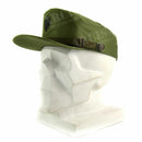 Olive green Spanish military visor cap with front emblem and adjustable chin strap on white mannequin head