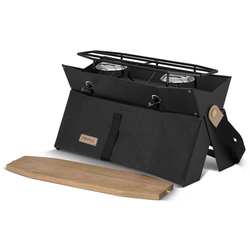 Compact Primus Onja dual burner camping stove with foldable design and wooden windscreen for outdoor cooking.